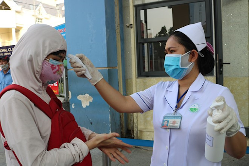 Kiểm tra thân nhiệt, sát khuẩn trước khi vào bệnh viện. Ảnh: HCDC